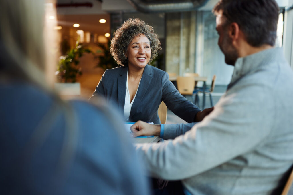 Happy insurance agent talking to her customers in the office.