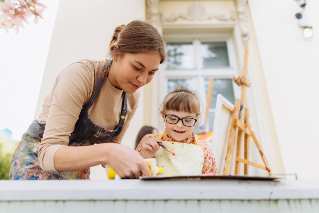 The art therapist help painting to girl with a mental disability
